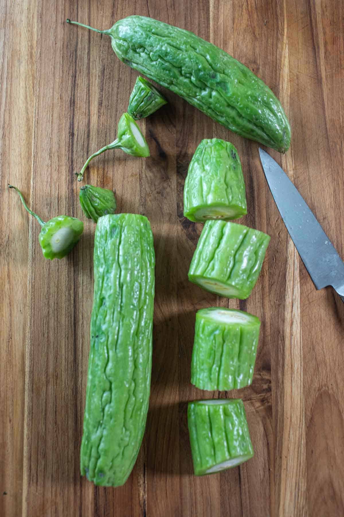 whole and sliced Bitter melons on a cutting board. 