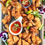 butterfly shrimp on a tray rack with dipping sauce and garnishes.