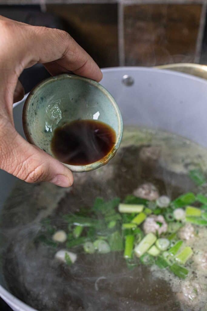 Saucing pouring in a strainer over a soup pot. 