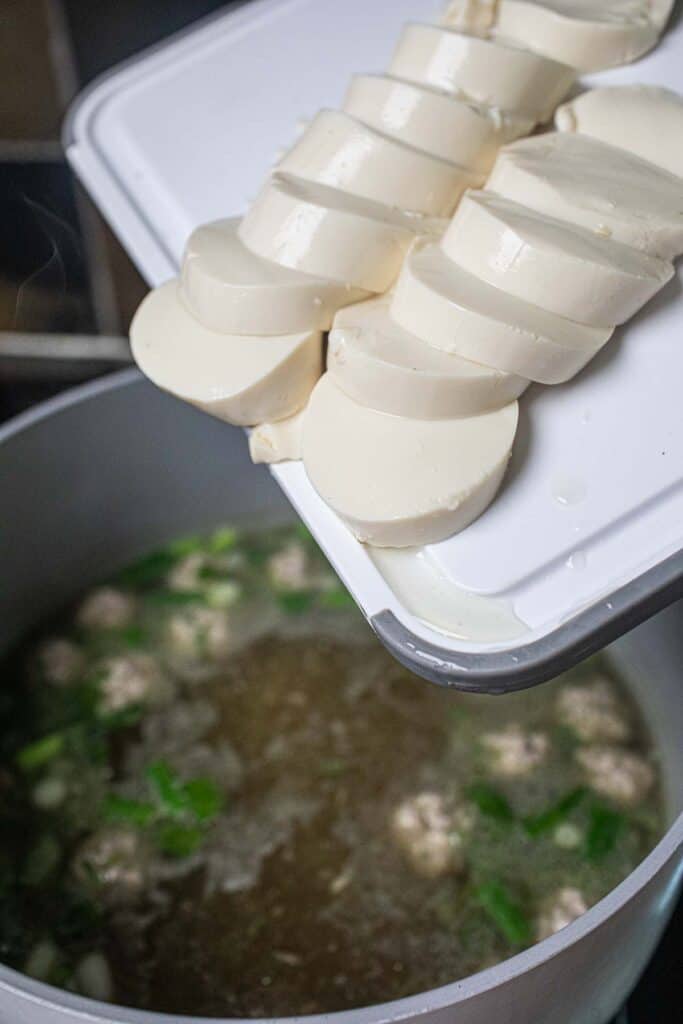 Tofu pouring over a soup pot. 