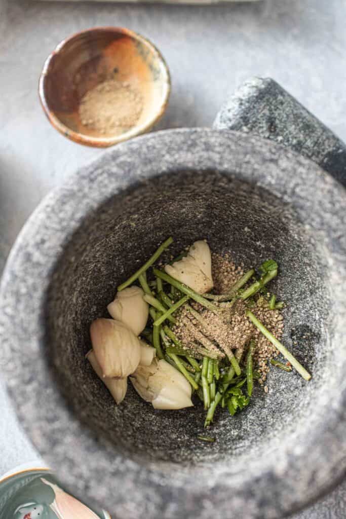 Garlic, cilantro and white pepper in a mortar. 