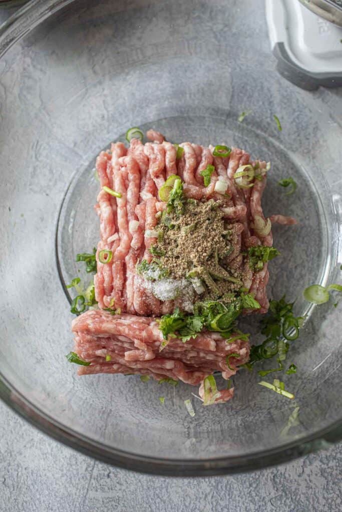 Pork mixture for meatballs in a glass bowl. 