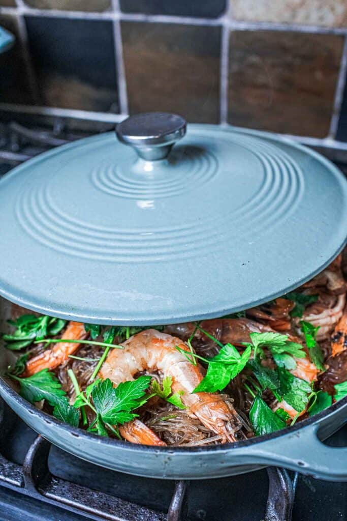 Glass noodles in a skillet with a lid. 