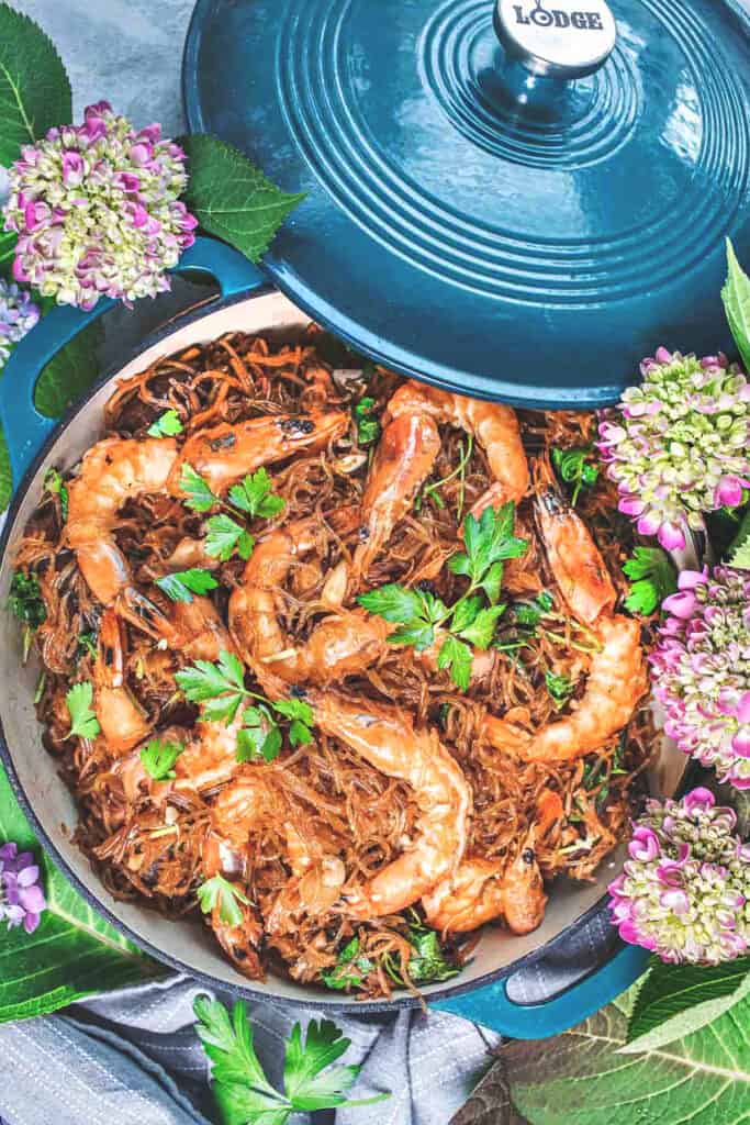 jumbo shrimp over glass noodles in a large pan.