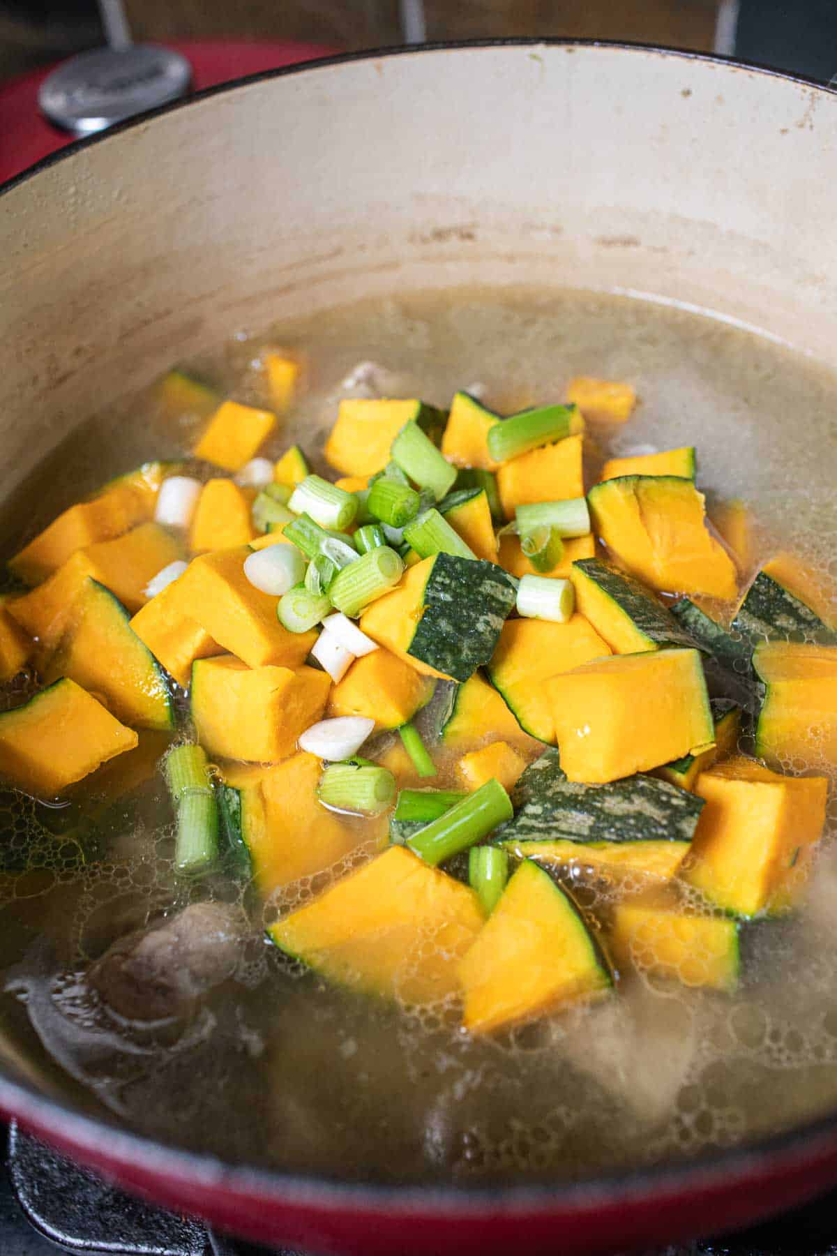 Kabocha squash in a broth in a stock pot. 