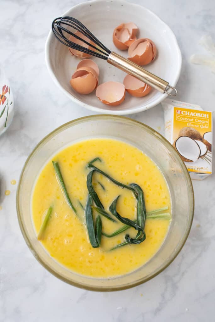 scrambled Eggs and pans leaves in a bowl with coconut milk.