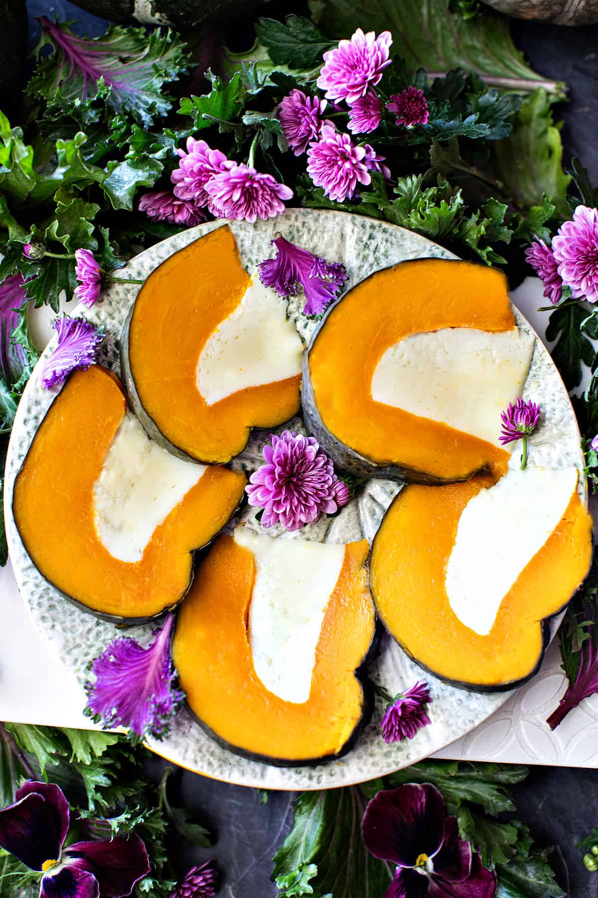 Thai pumpkin custard in slices on a plate with flowers garnish.