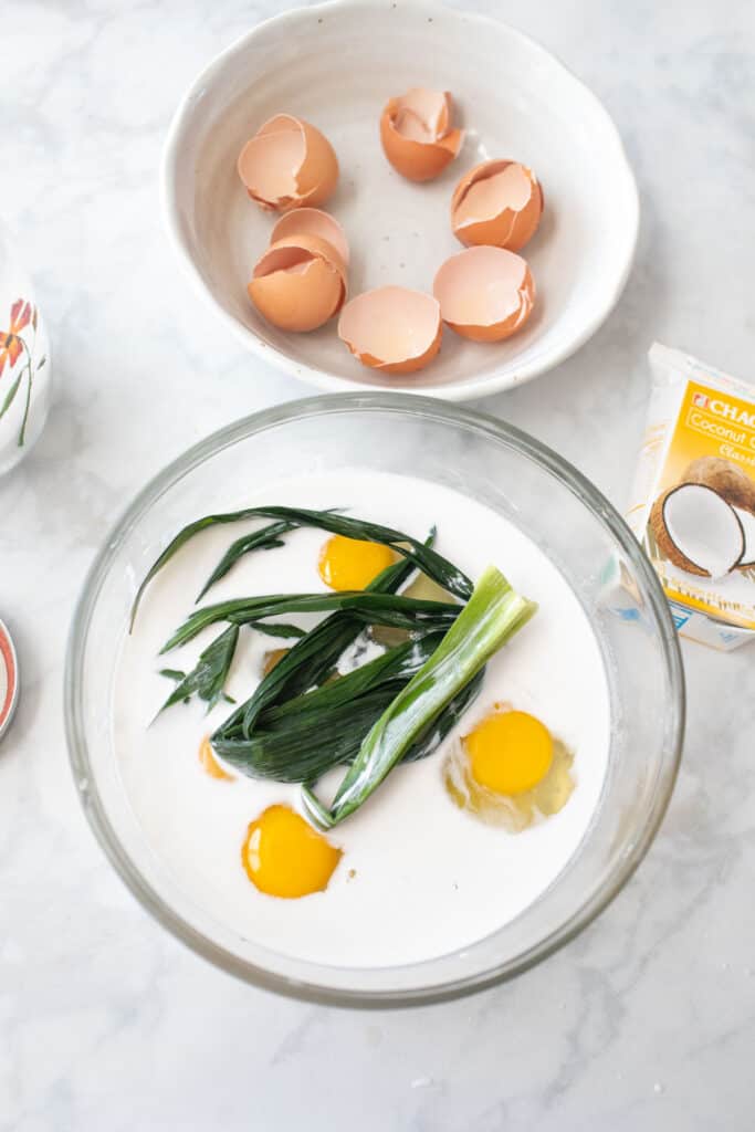 Eggs and pans leaves in a bowl with coconut milk.