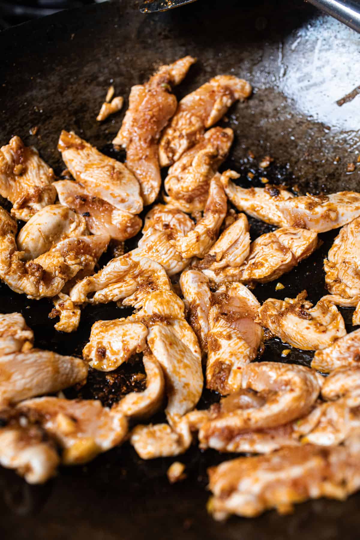 Chicken stir frying in a pan with curry sauce. 