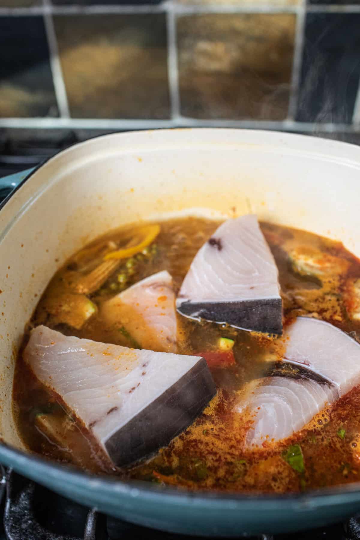 Fish fillets inside a pot of jungle curry. 