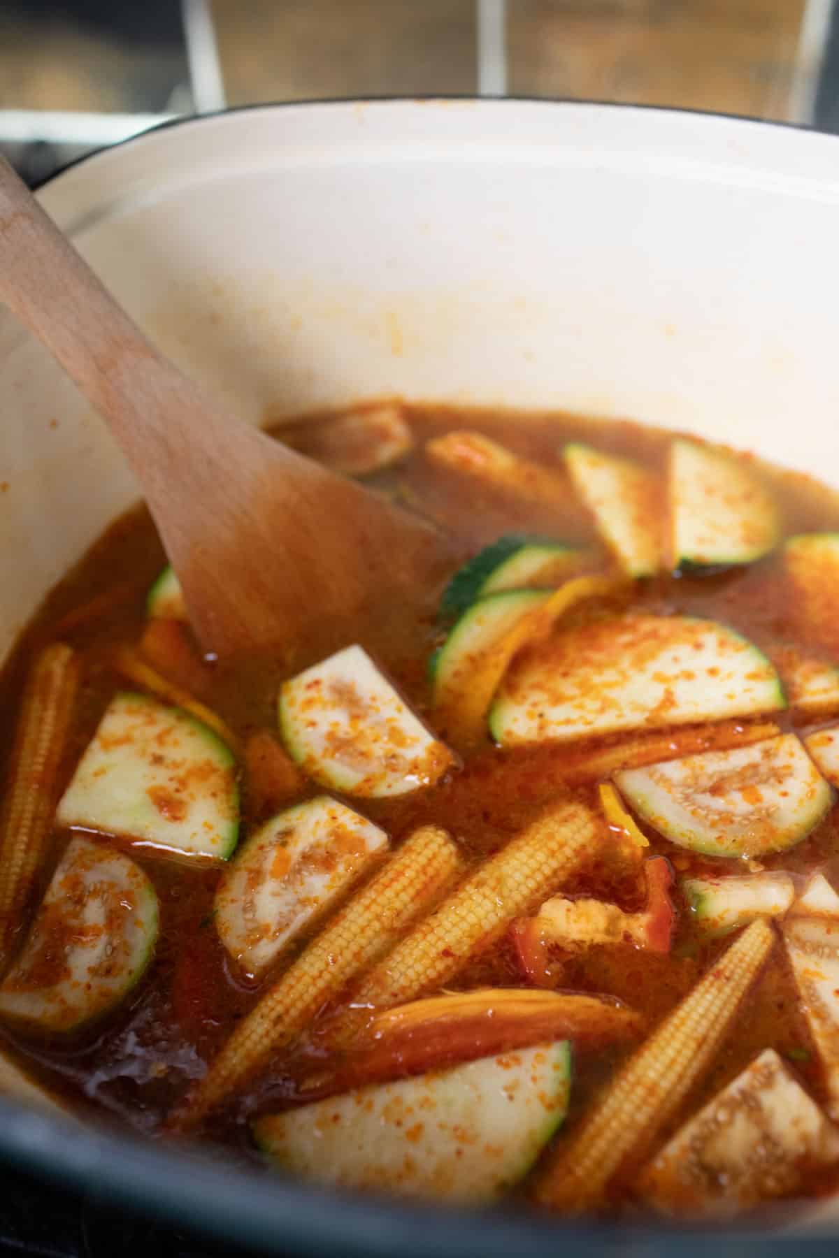 Vegetables inside a pot of jungle curry on the stove. 