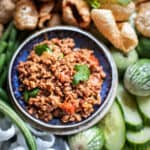 Nam Prik Ong dip surrounded by vegetables and pork rind.