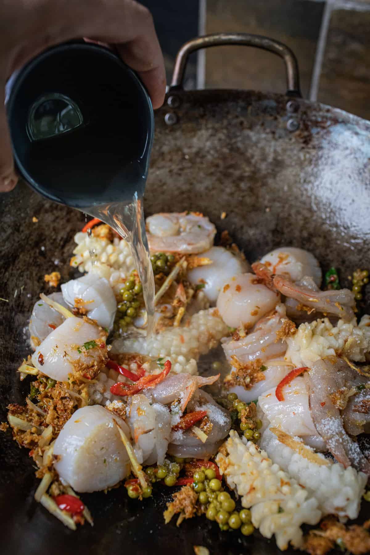 Stock pouring over pad cha paste in a wok. 