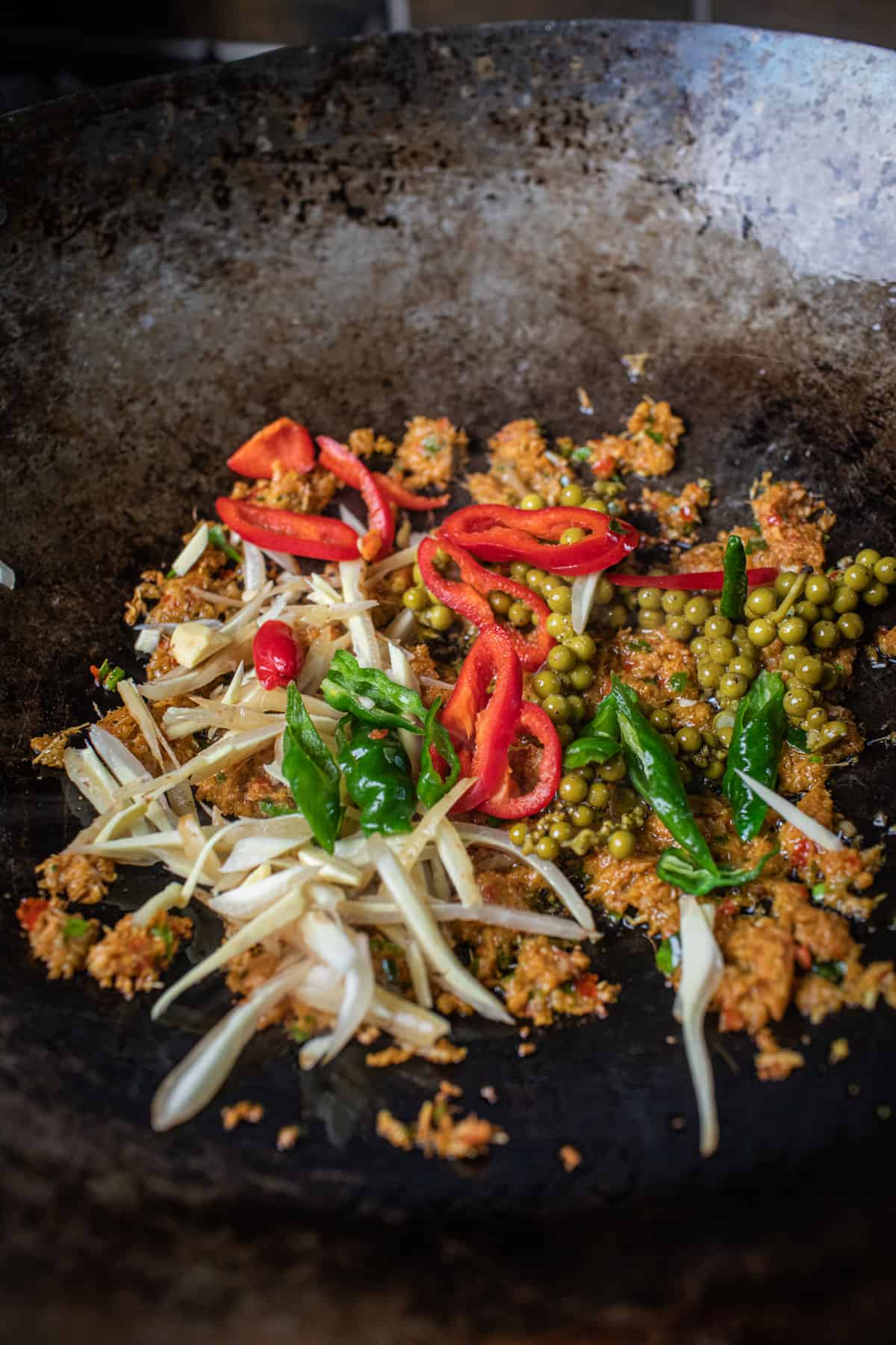 Pad cha paste and fresh herbs frying in a wok. 