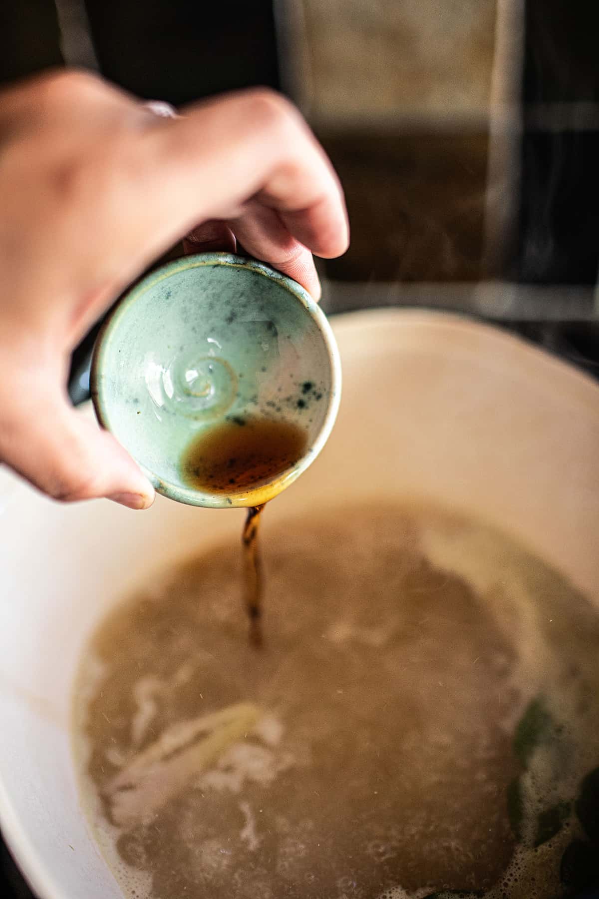 Fish sauce pouring into a pot of tom kha broth.