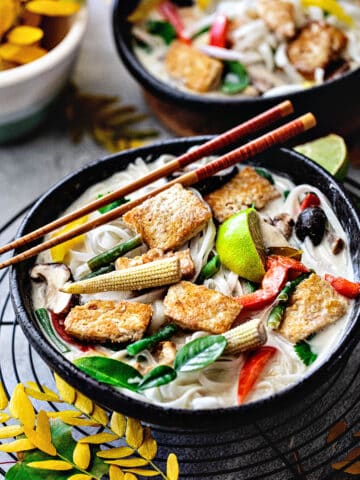 Tofu Tom Kha soup in a bowl with chopsticks on top.