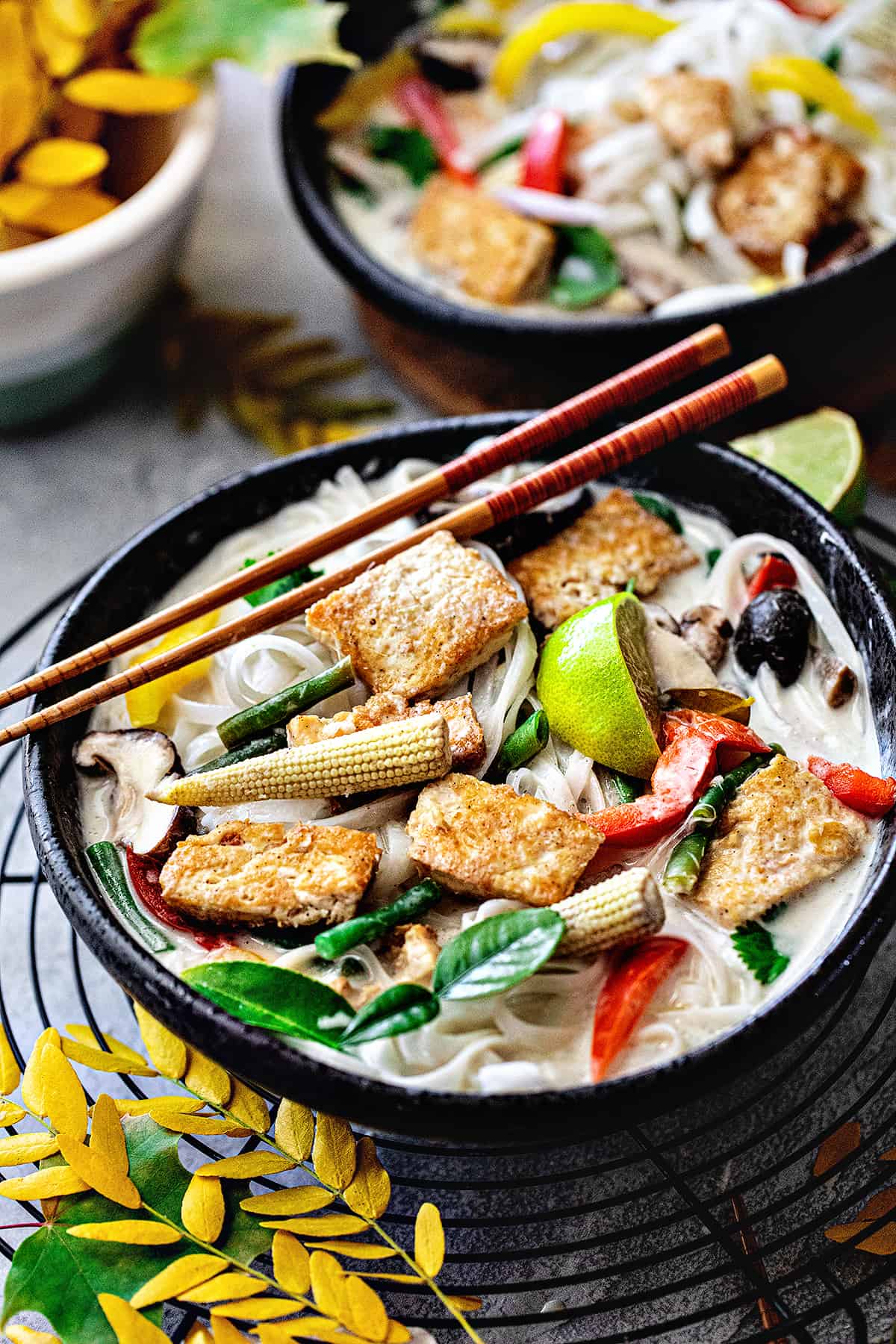 Tofu Tom Kha soup in a bowl with chopsticks on top.