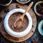 5 Spice powder in a white bowl with a spoon in the middle.