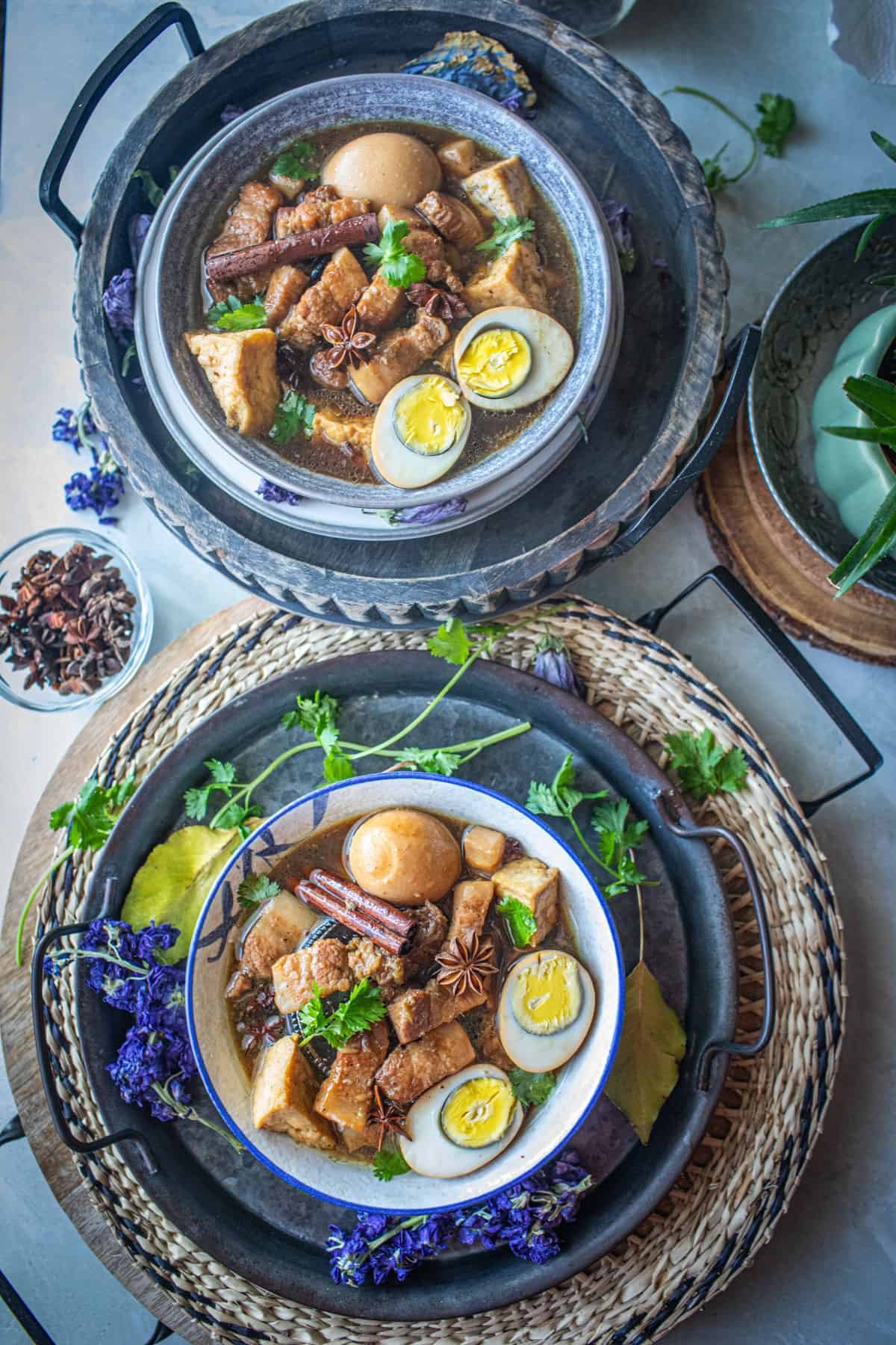 Pork Palo in bowls on the table with flowers and herbs around.