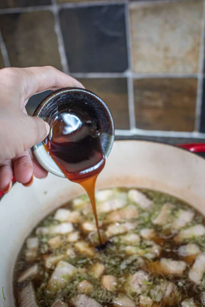 Sauce pouring into a pot of pork stew. 