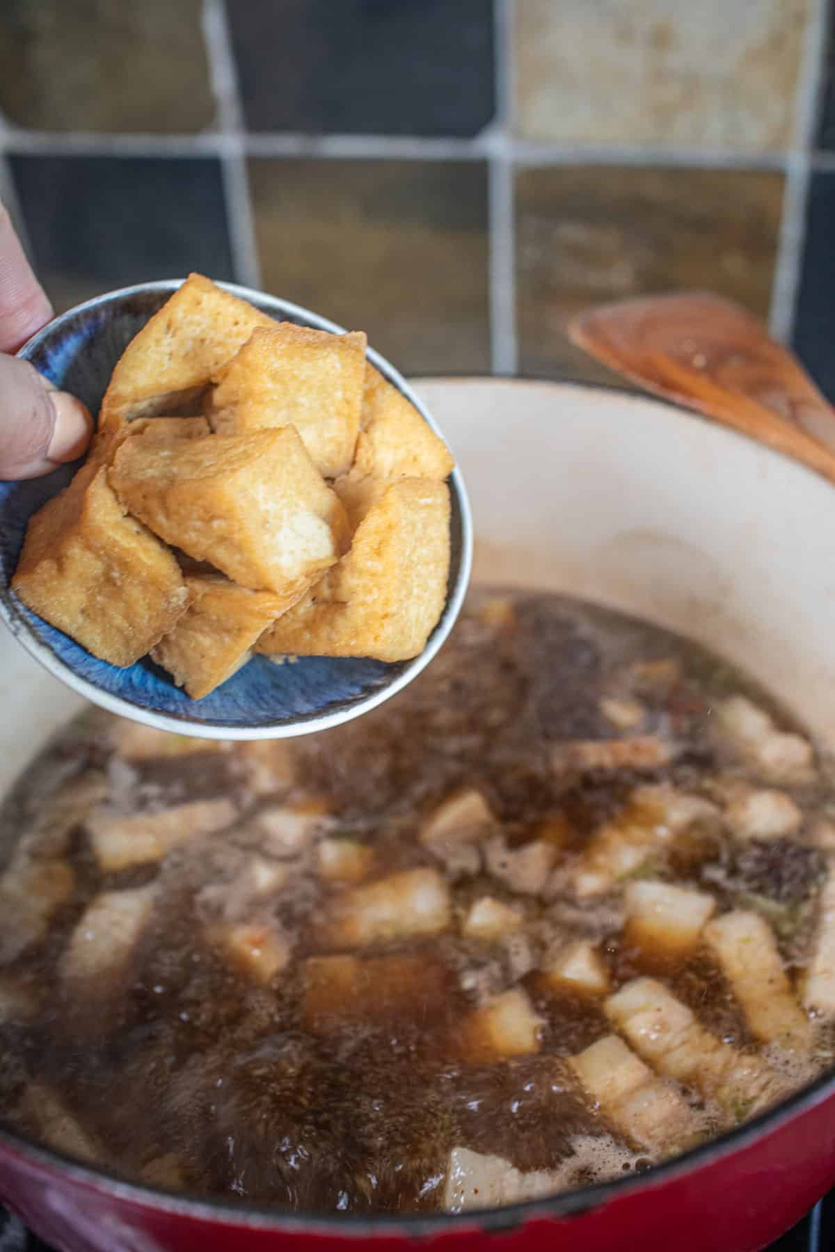 Fried Tofu pouring into a pot of pork stew. 