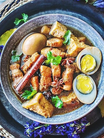 Thai pork belly stew with sliced hard boiled eggs in a bowl.