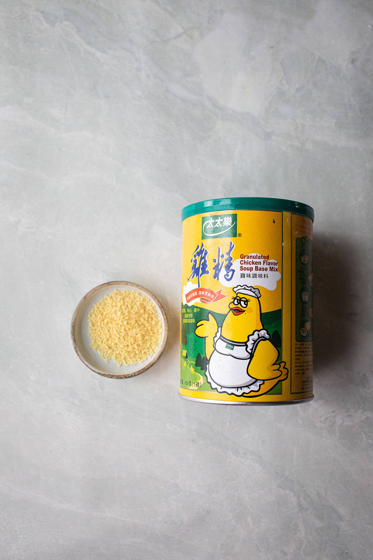 Granulated chicken powder container and small plate on the table. 
