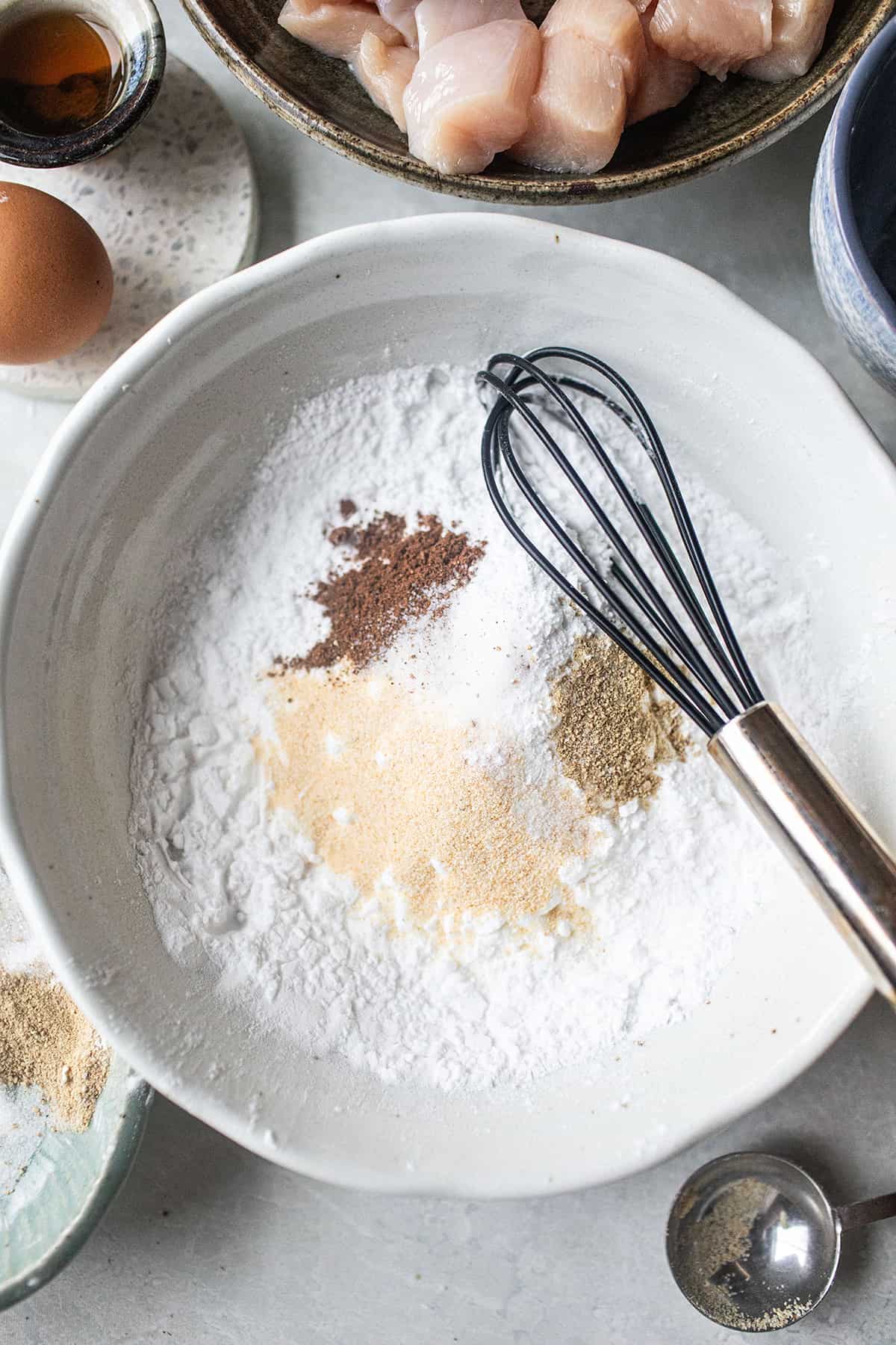 Flour and spices in a mixing bowl with a whisk. 