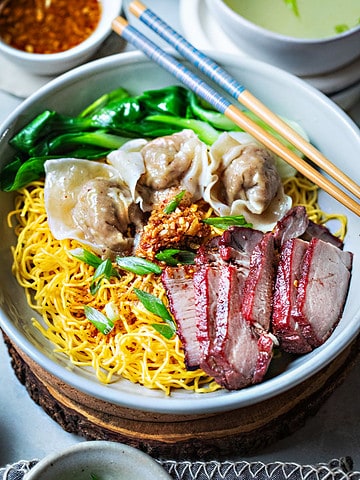 bamee moo dang noodles in a bowl with red pork and wontons.