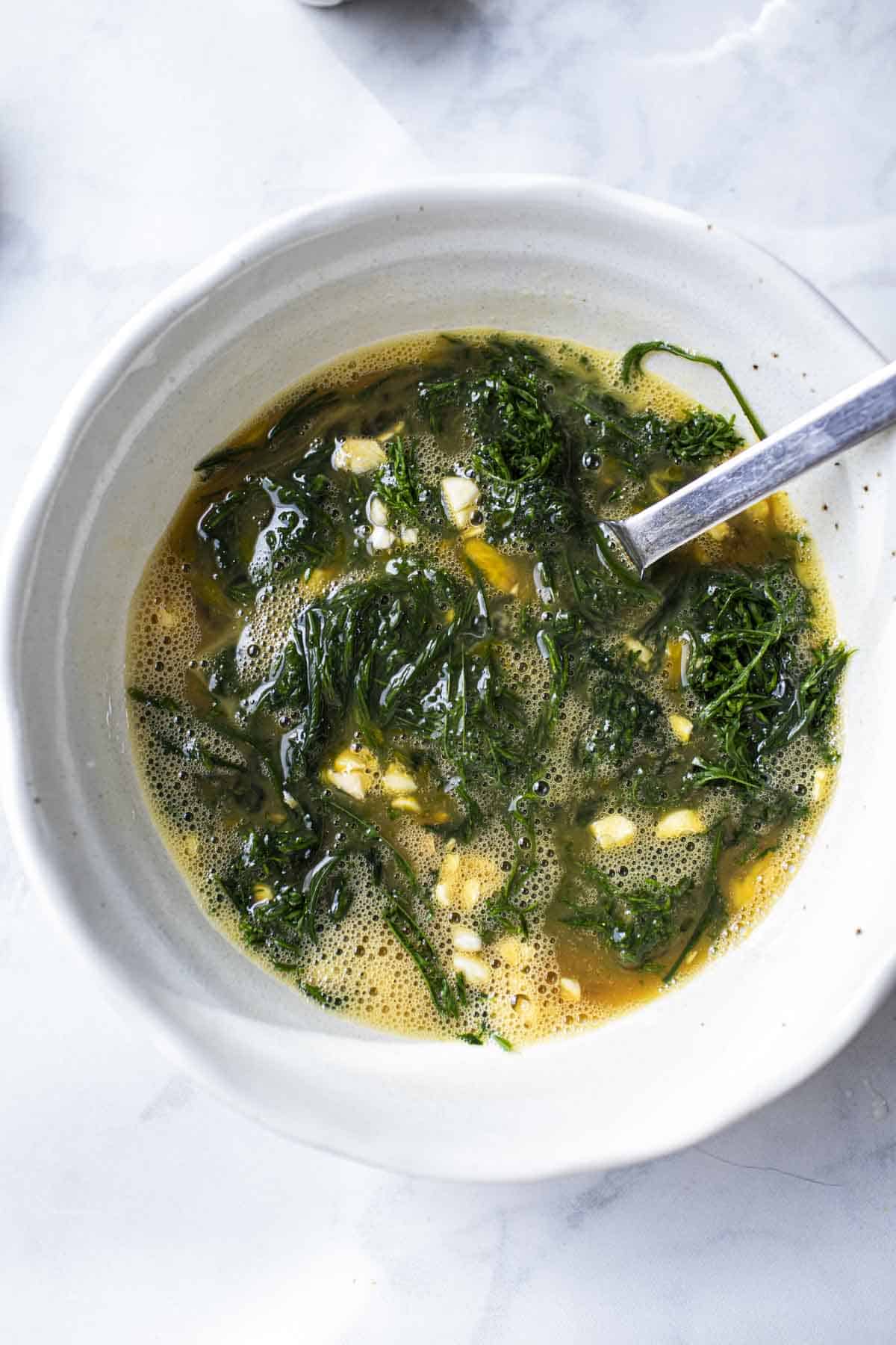 Whisked eggs with Acacia leaves mixed in a bowl for Thai omelette.