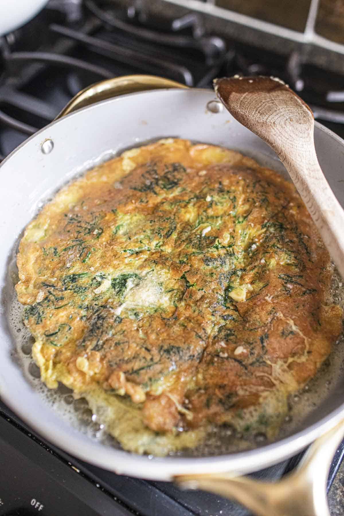 Fried Cha Om Thai Omelete in a pan on the stove. 