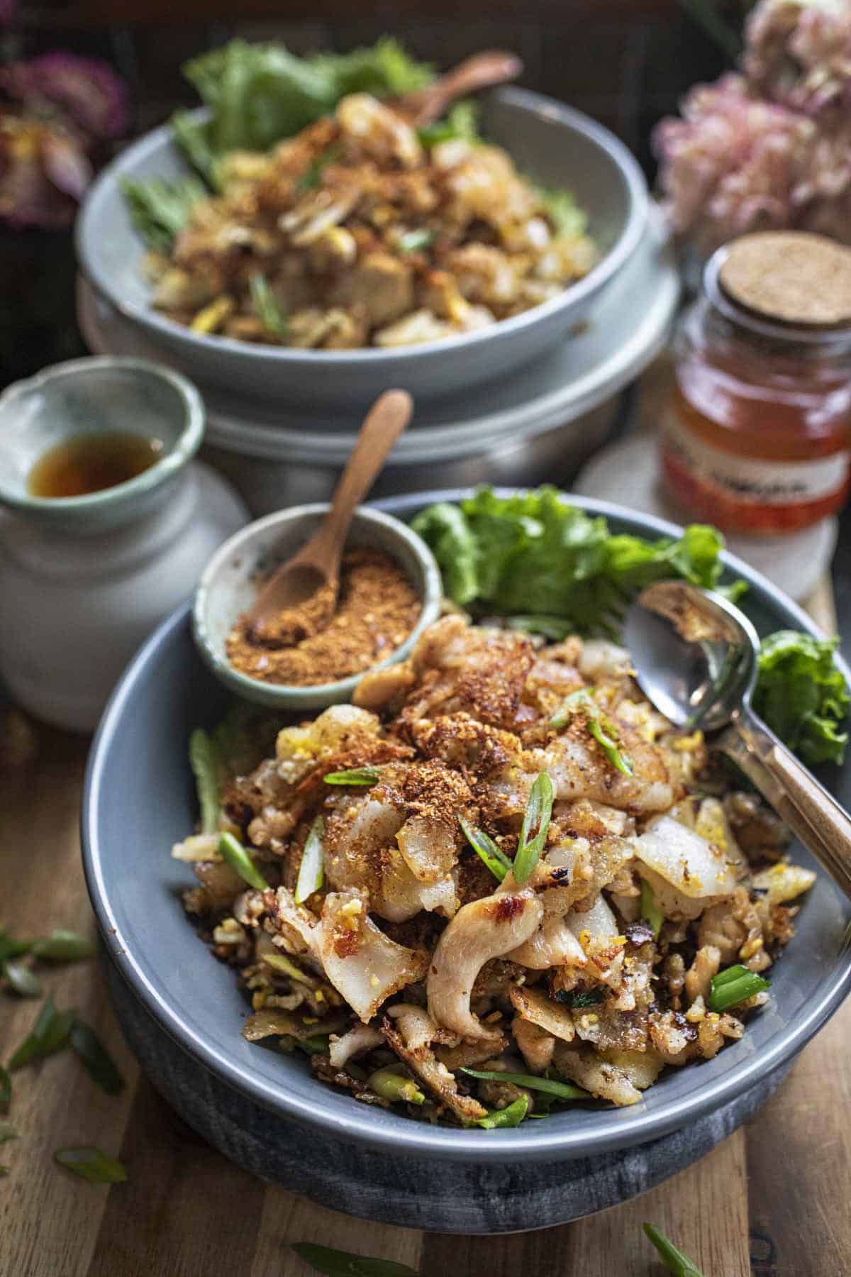 Guya Tiew Kau Gai on a plate with chili flakes on the side. 