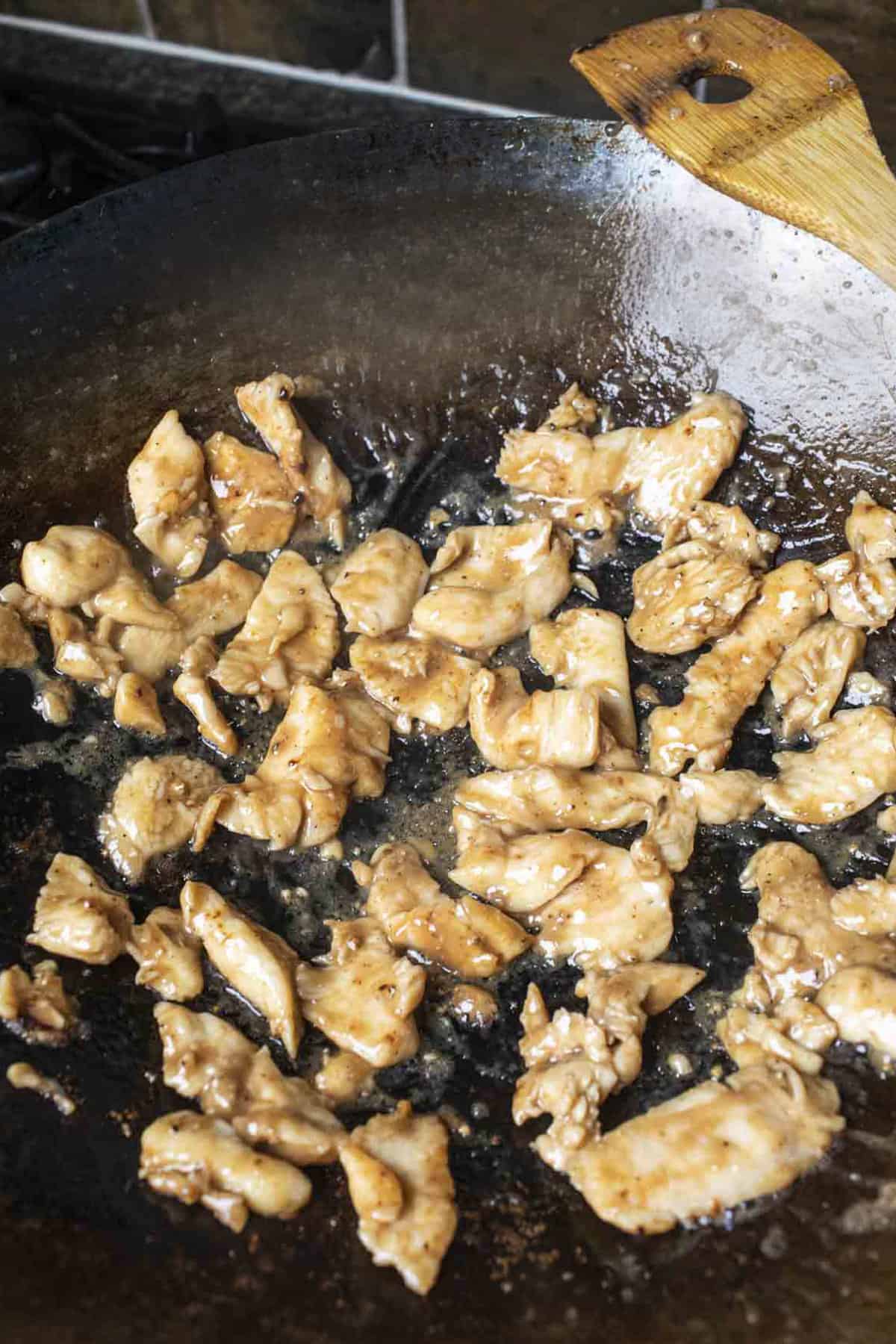 stir fry chicken pieces in a wok. 