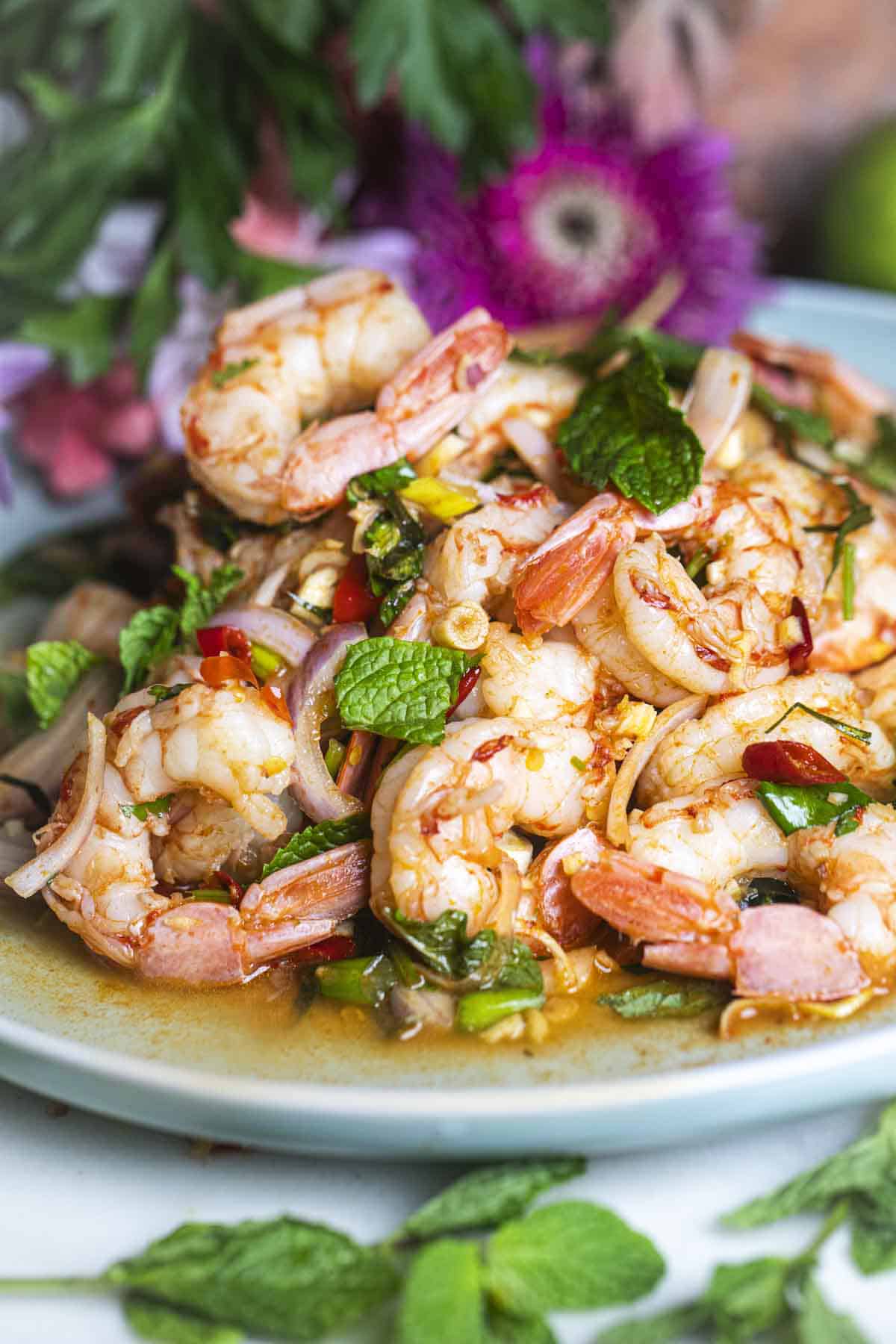 Pla Goong Shrimp Salad on a platter surrounded by flowers and greens.