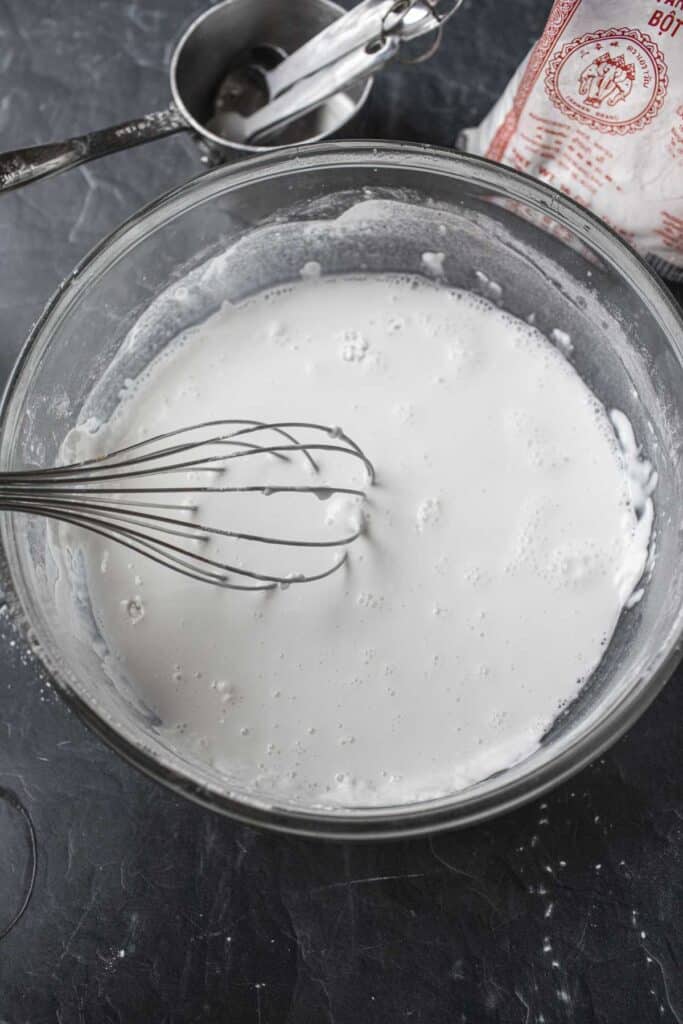 White rice Flour liquid and whisk in a glass bowl on the table. 