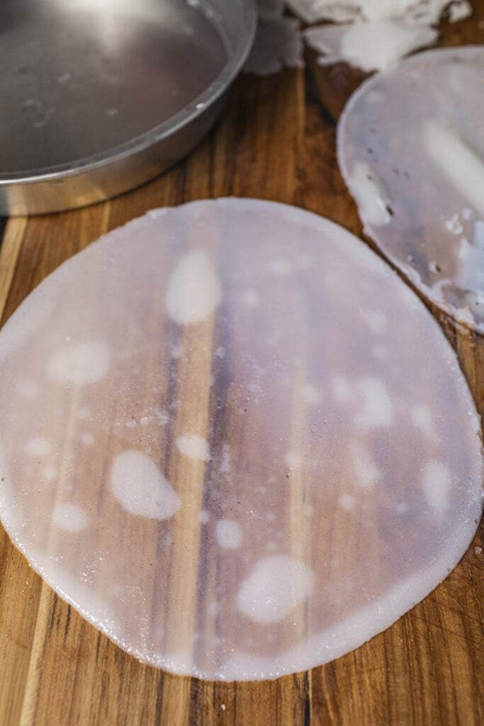 Clear round rice noodle on a cutting board. 