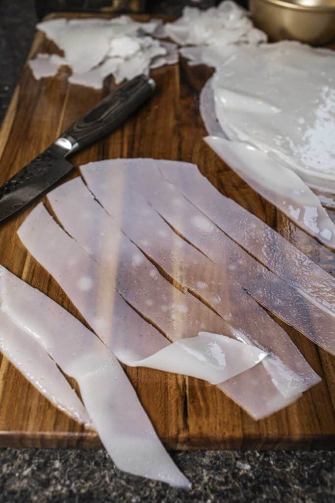 Cut rice noodle strips on a cutting board. 