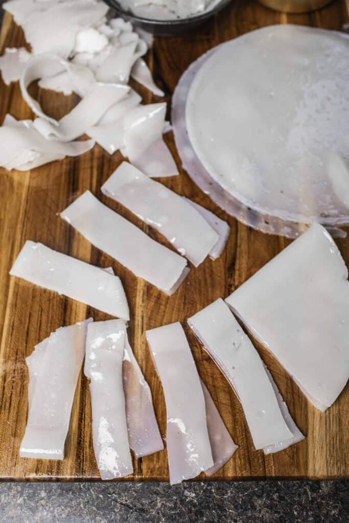 Cut rice noodle strips on a cutting board. 