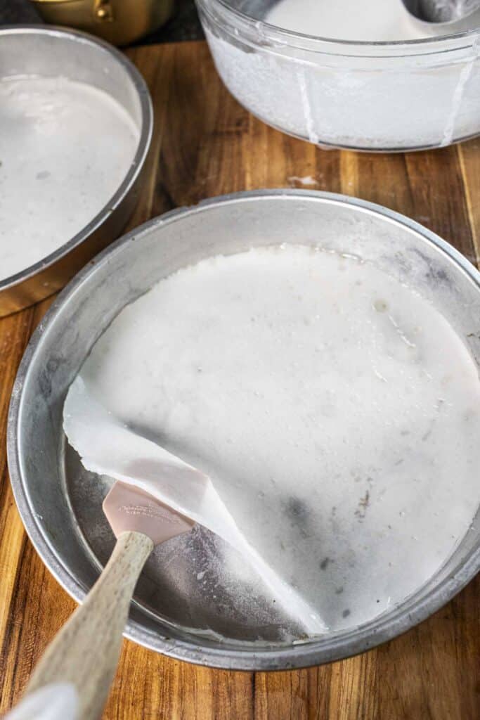 A spatula lifting cooked rice noodles in a baking pan.