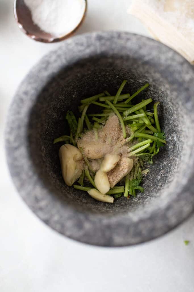 A green paste ingredients in a pestle. 