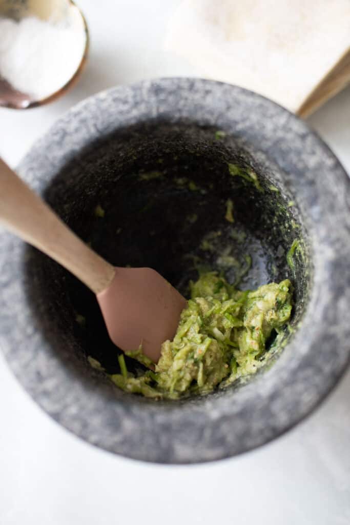 A green paste in a pastle with a spatula.