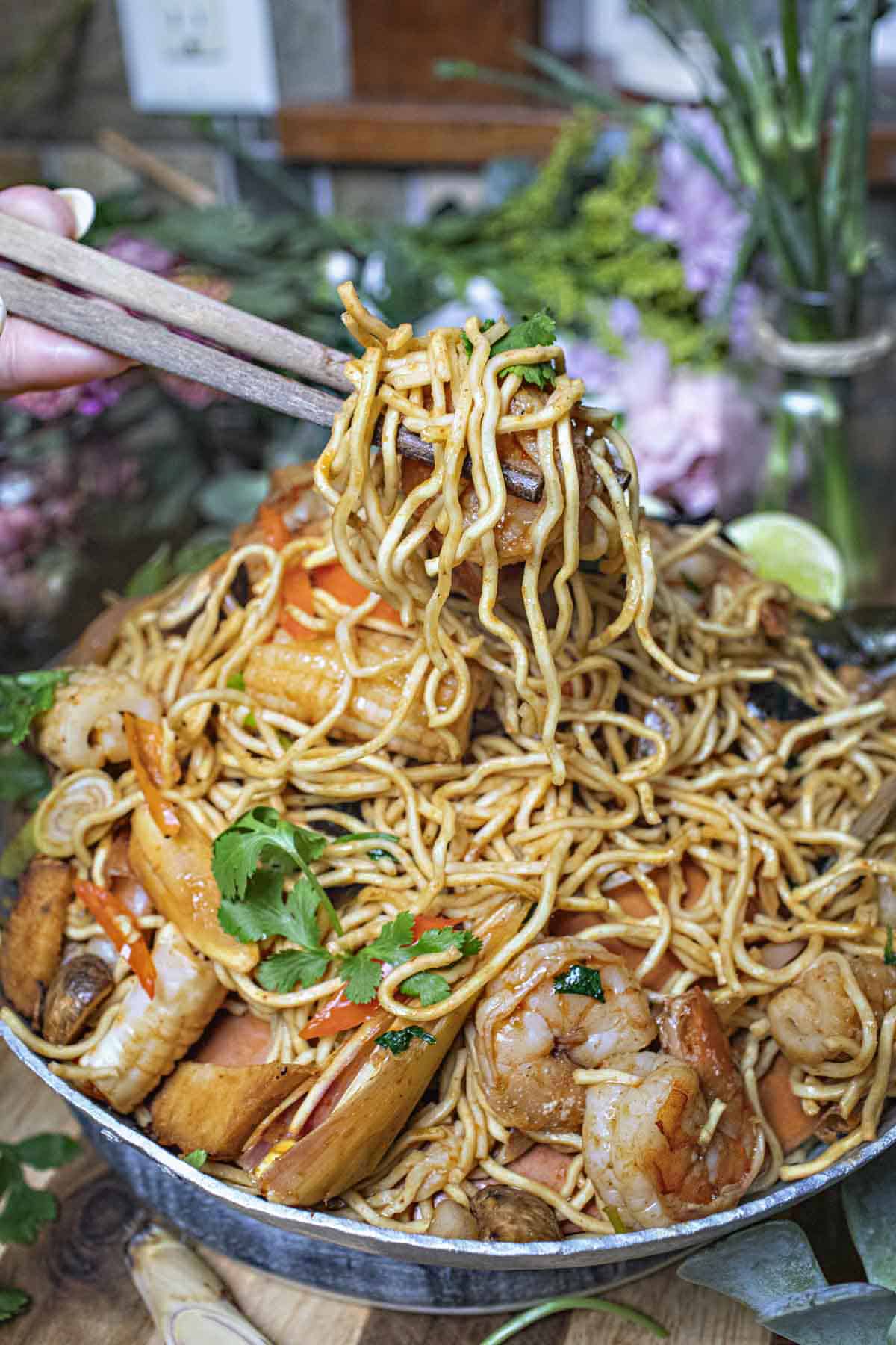 Chop sticks lifting Tom Yum Noodles from a bowl. 