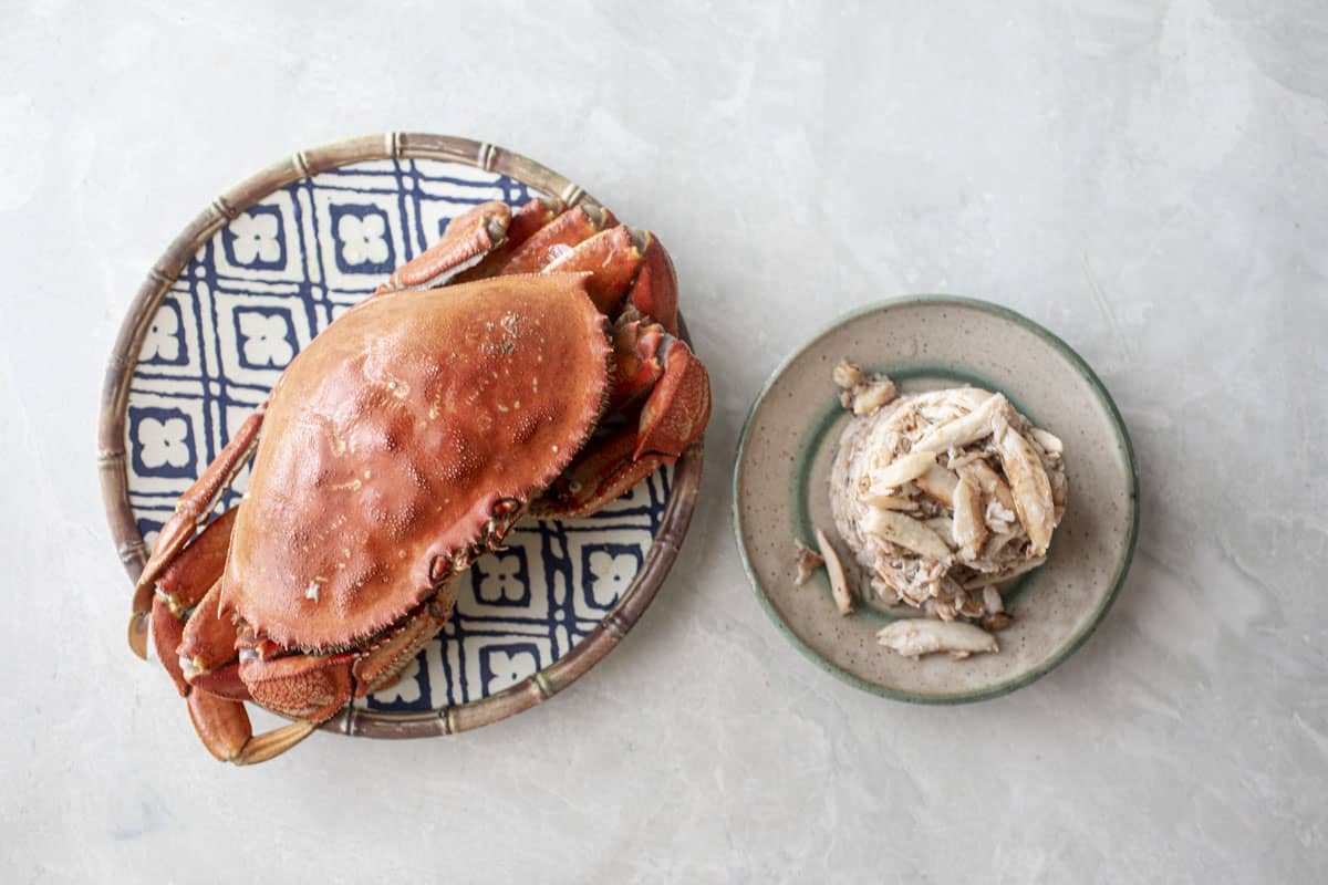 Whole crab and crab meat slices on platters next to each other. 