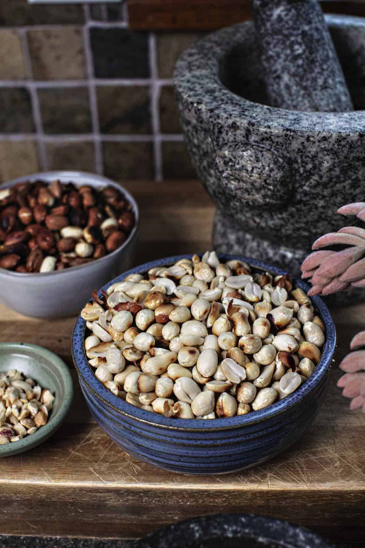 Toasted peanuts in a bowl on cutting board. 