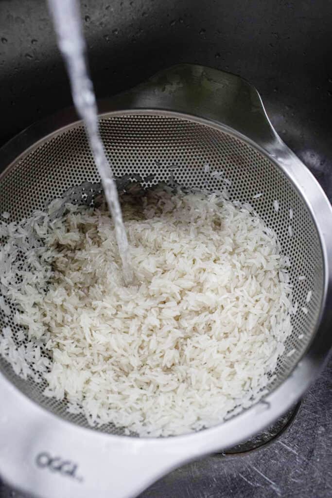 Water rinsing rice in a colander. 