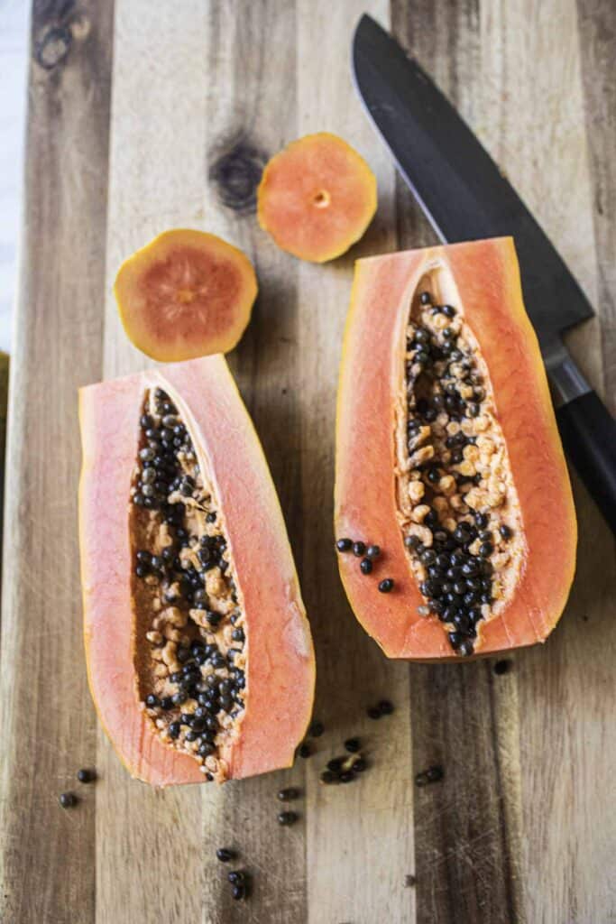 Ripe Orange papaya in 2 halves on a cutting board. 