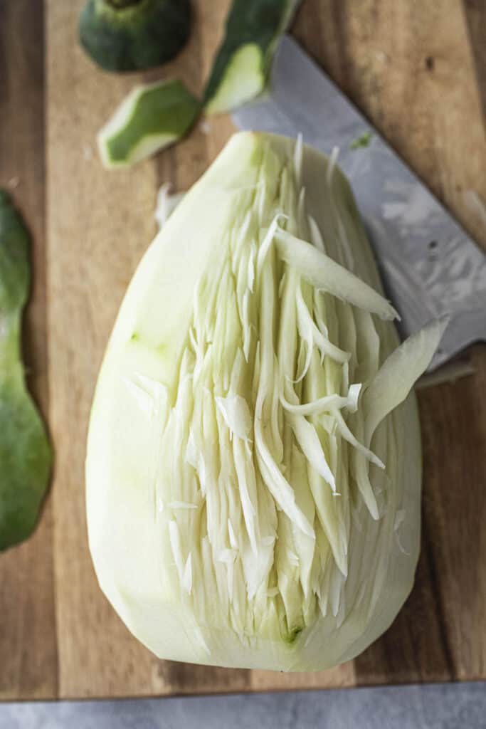 Shredded young green papaya on a cutting board. 