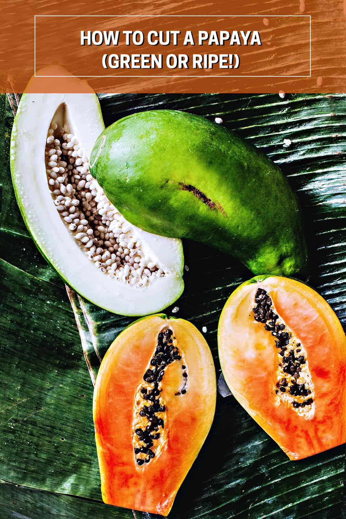 Green and orange papayas on a banana leaf. 