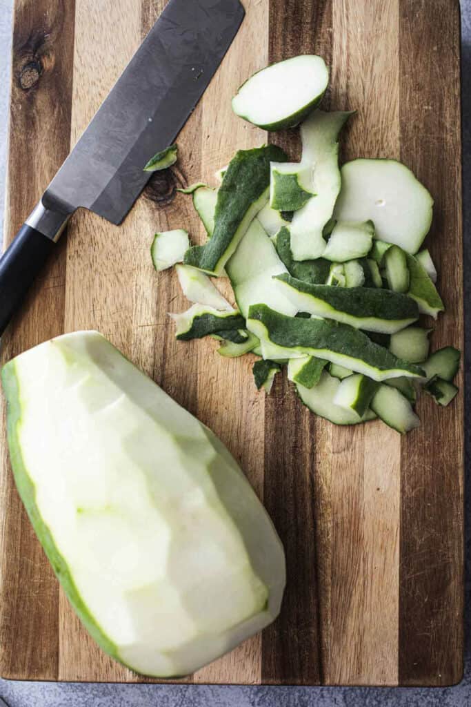 green papaya with skin peeled on a cutting board. 