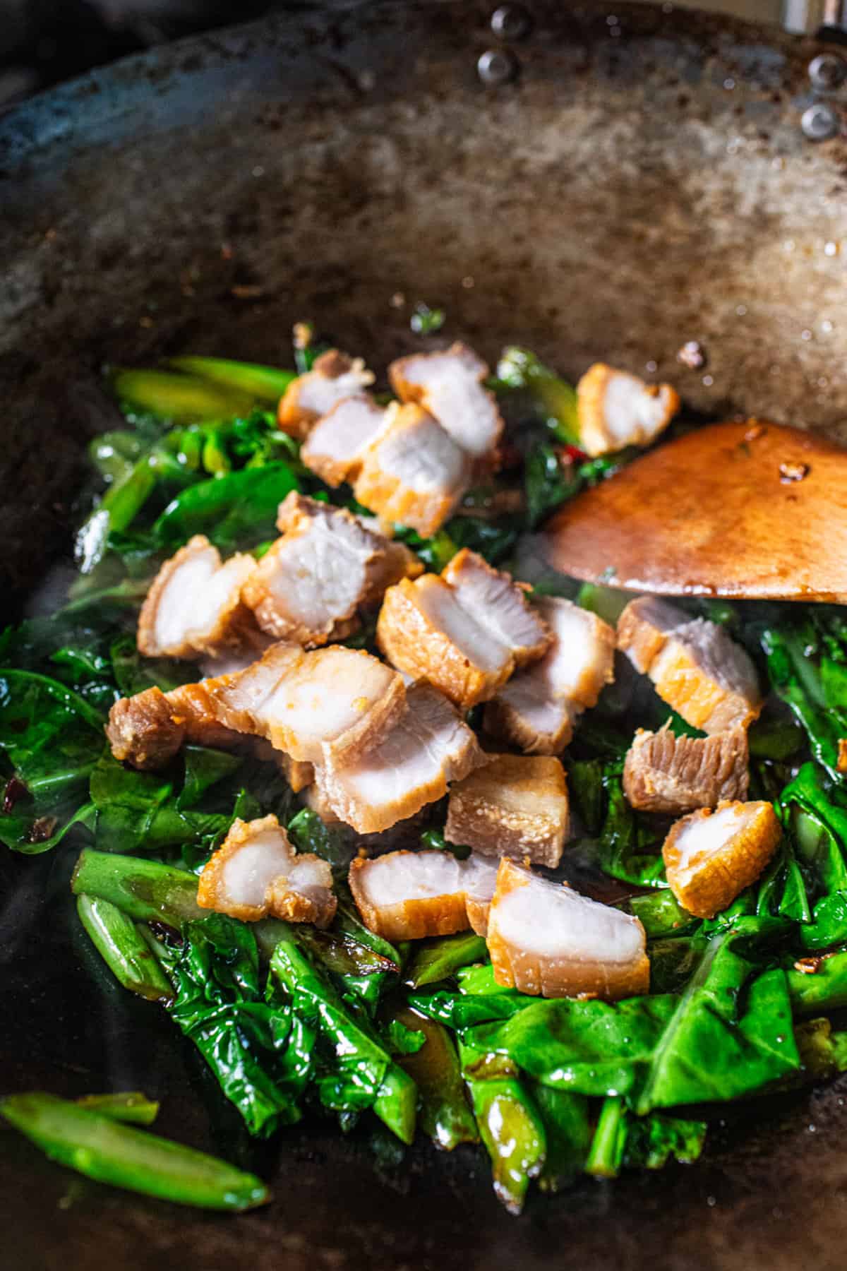 crispy pork belly and Chinese broccoli in a wok for pad kana recipe.